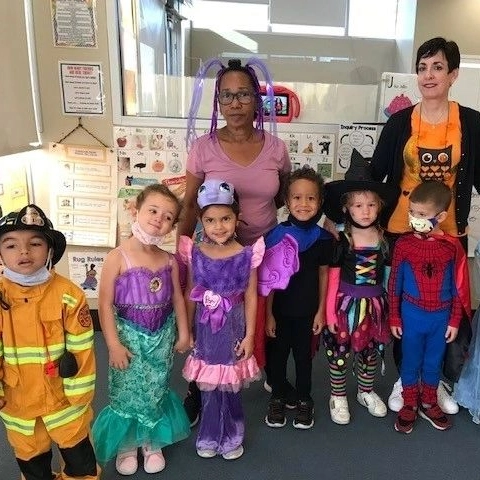Children in colorful costumes with teachers