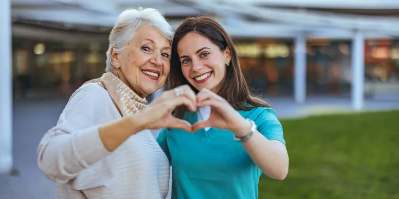 Two women posing with heart gesture