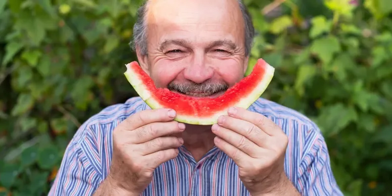 Happy man enjoying watermelon outdoors